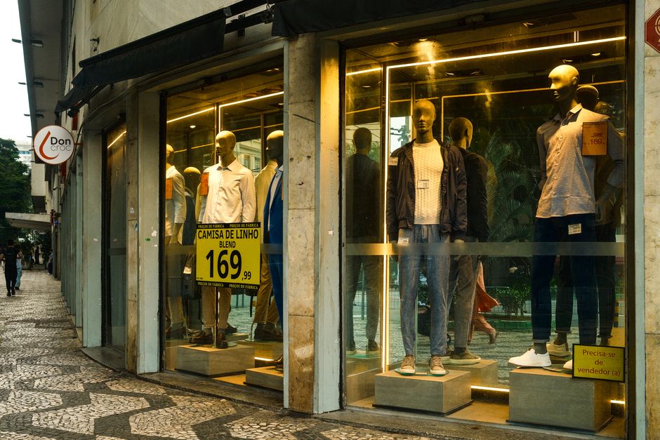 Exibição de moda masculina estilosa em uma vitrine de São Paulo com manequins exibindo roupas modernas.